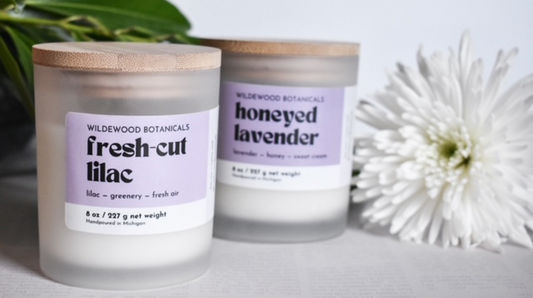 fresh-cut lilac and honeyed lavender candles in the regular size with a white flower in the background