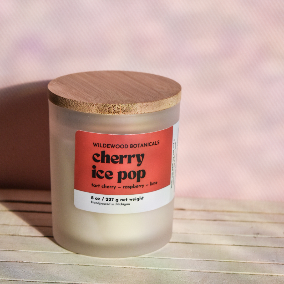 Cherry Ice Pop Soy Candle on a Pink background with a wood tabletop