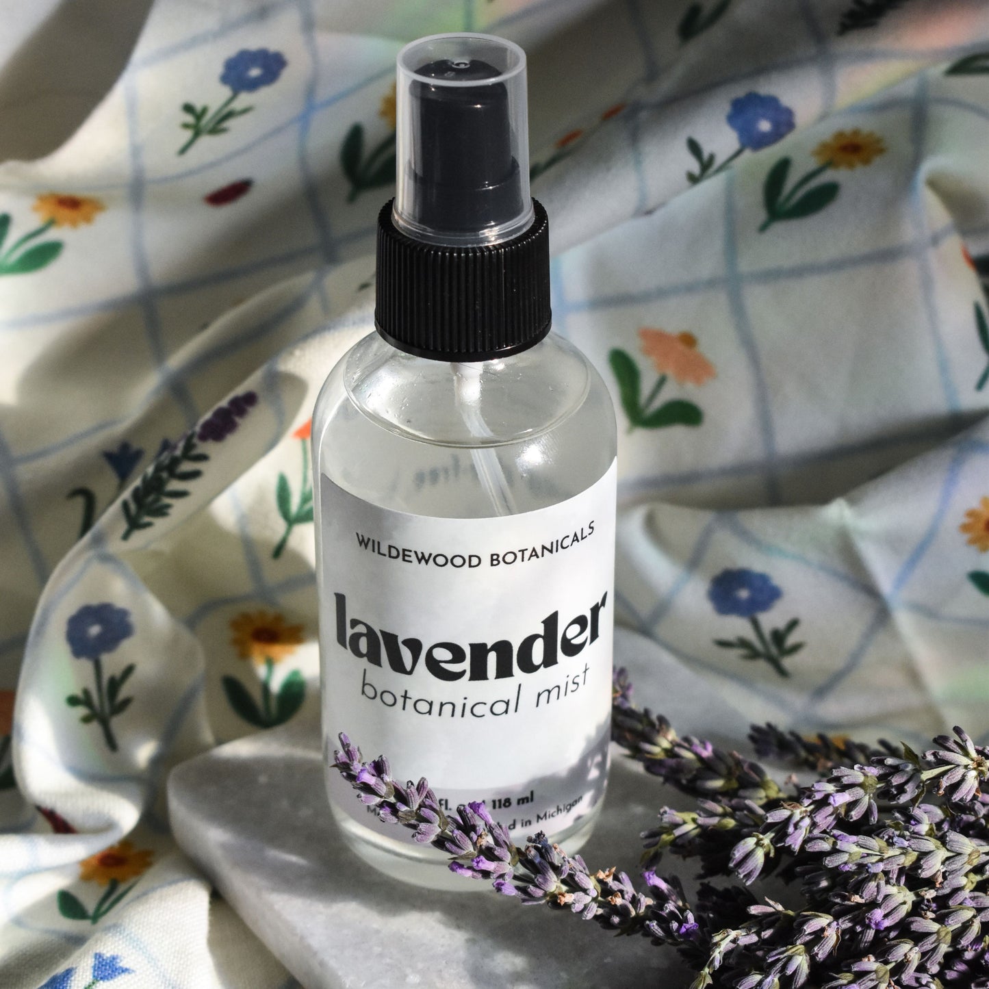 Bottle of Wildewood Botanicals lavender botanical mist on a floral cloth background