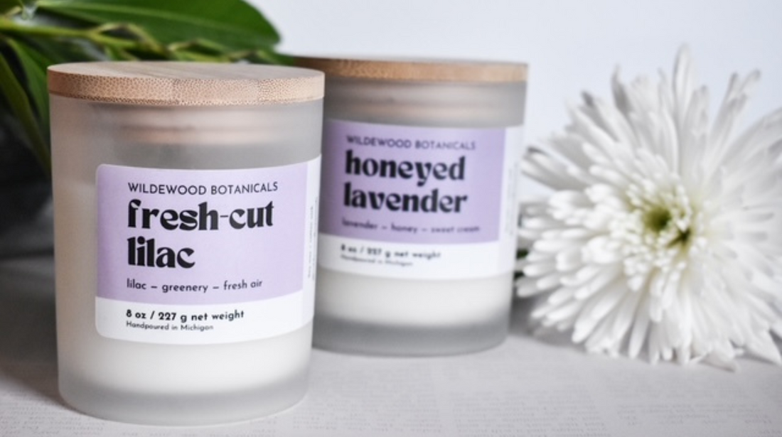 fresh-cut lilac and honeyed lavender candles in the regular size with a white flower in the background