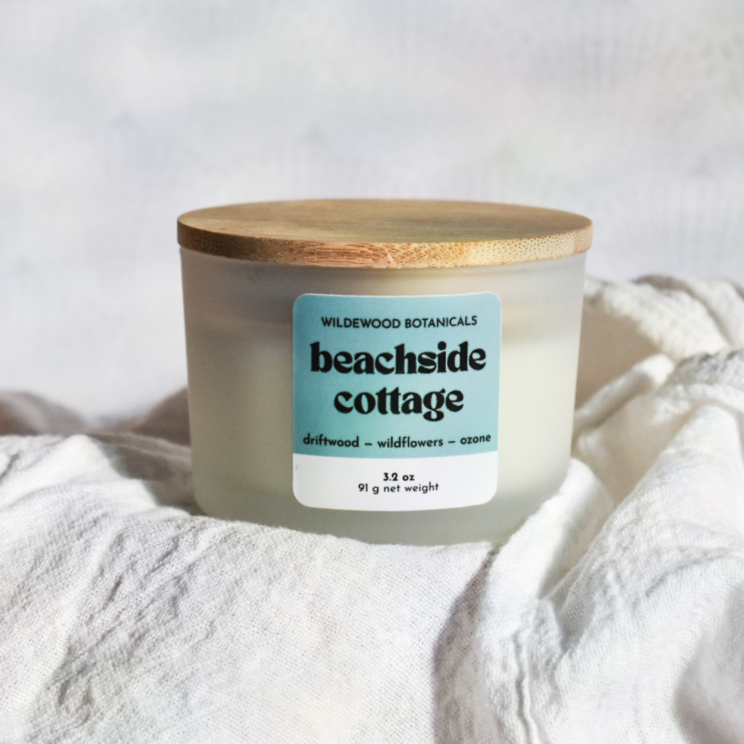 beachside cottage soy candle by wildewood botanicals sitting on a white linen towel