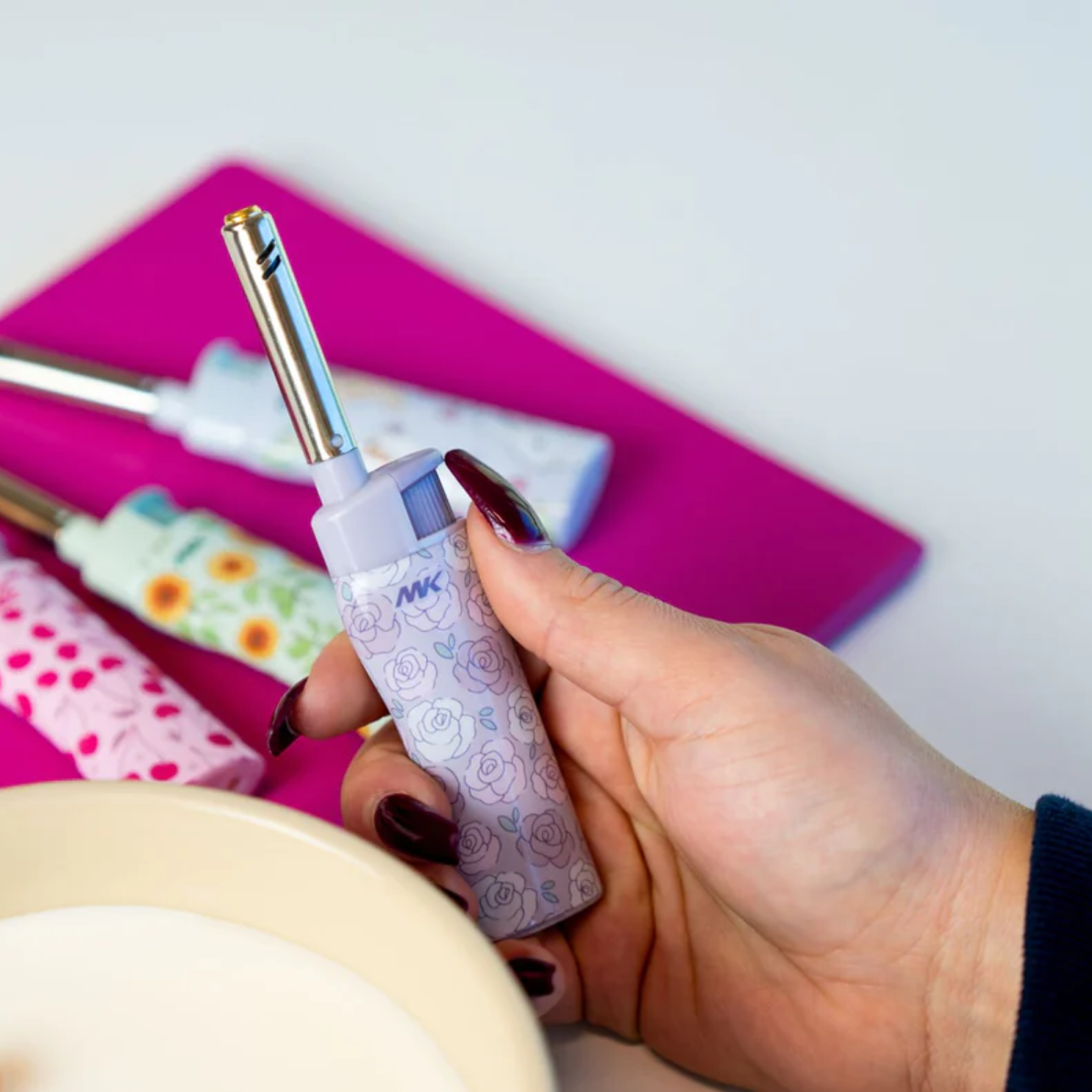 Hand holding a candle lighter tool from Wildewood Botanicals