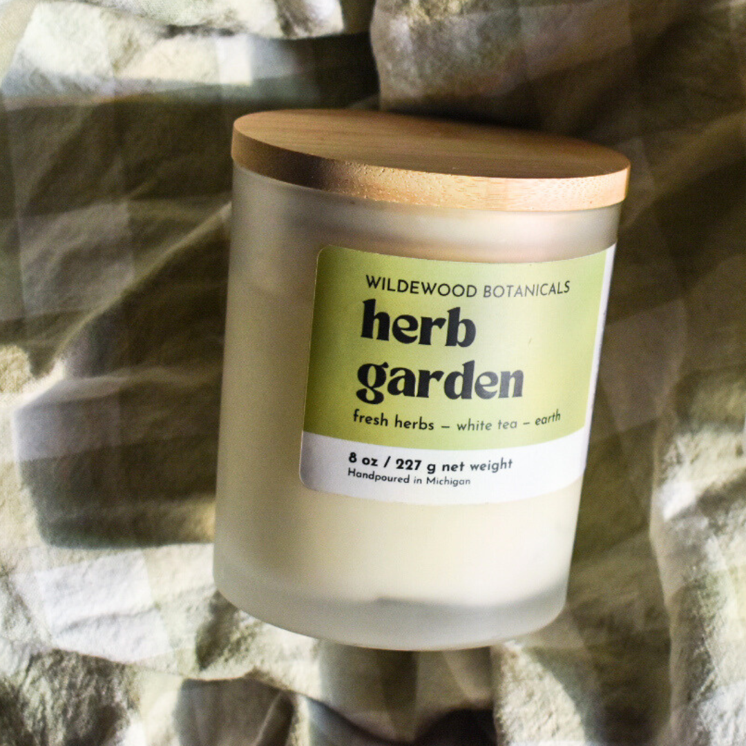 herb garden soy candle by wildewood botanicals on a green gingham towel