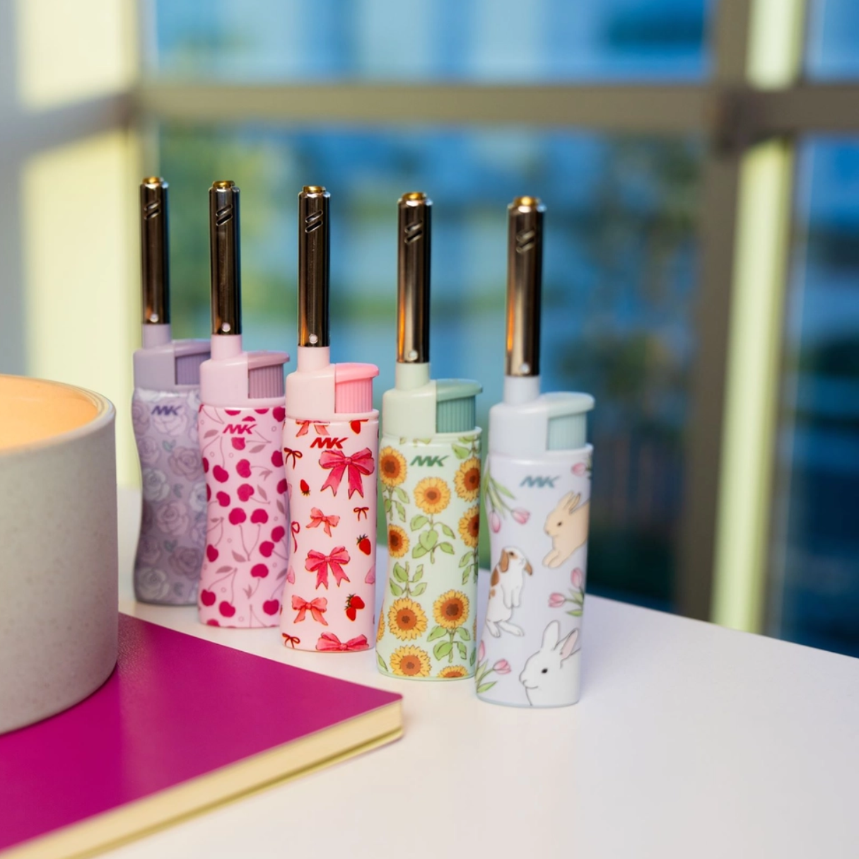 Set of five decorative candle lighters with long safety wand on a desk with a candle